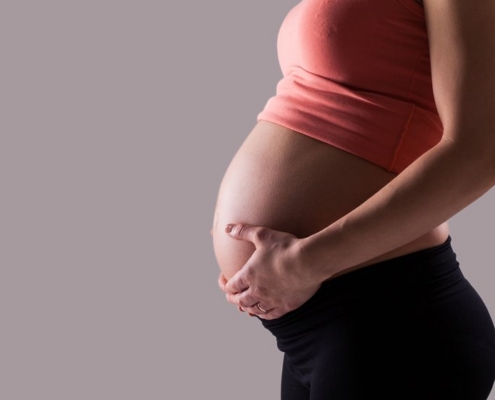 side facing pregnant torso, hands cradling bump